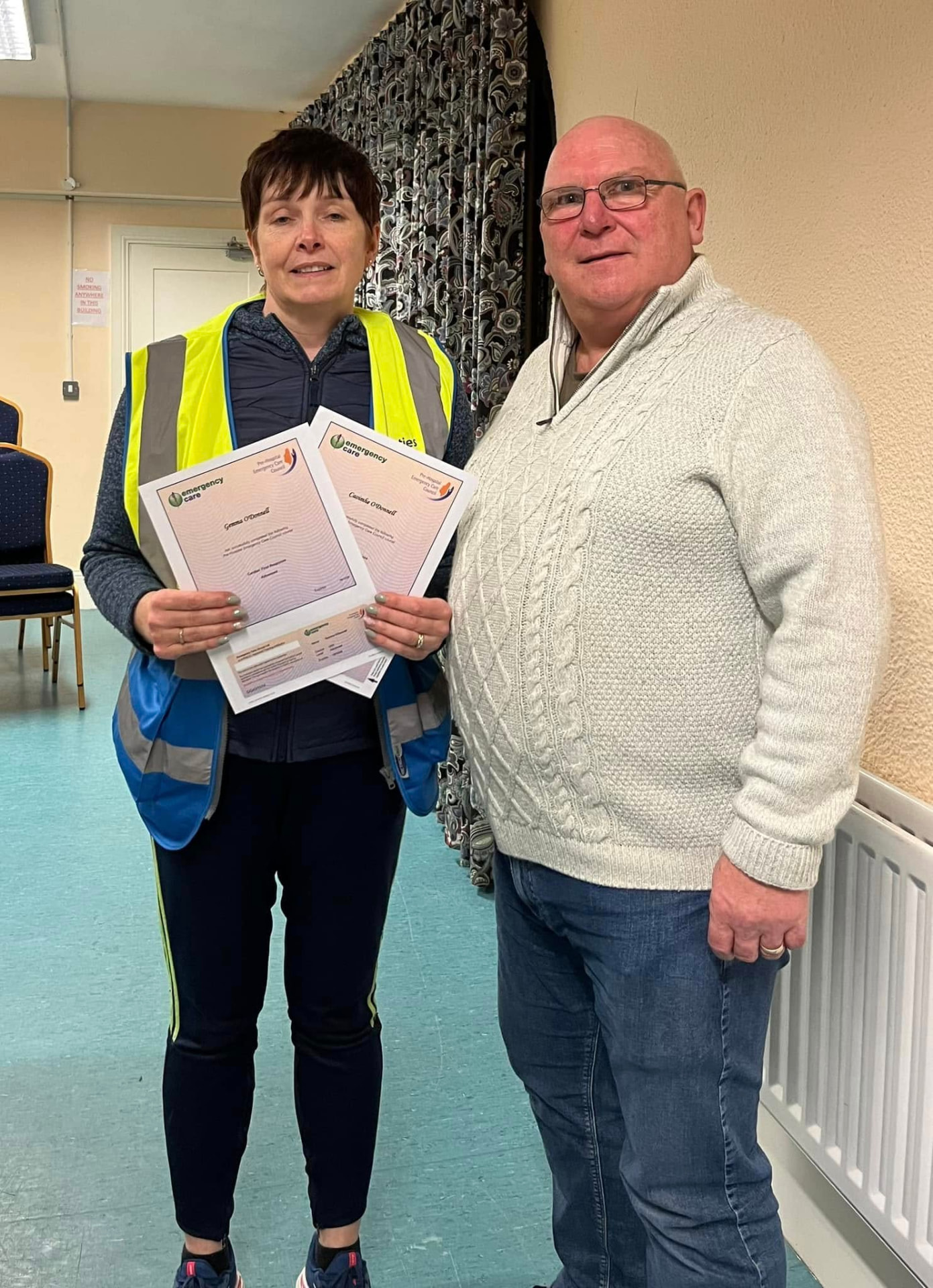 Two community members holding certificates after completing a training session