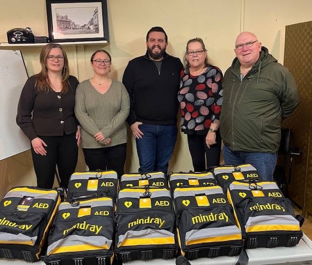 Community members standing behind a row of AED units