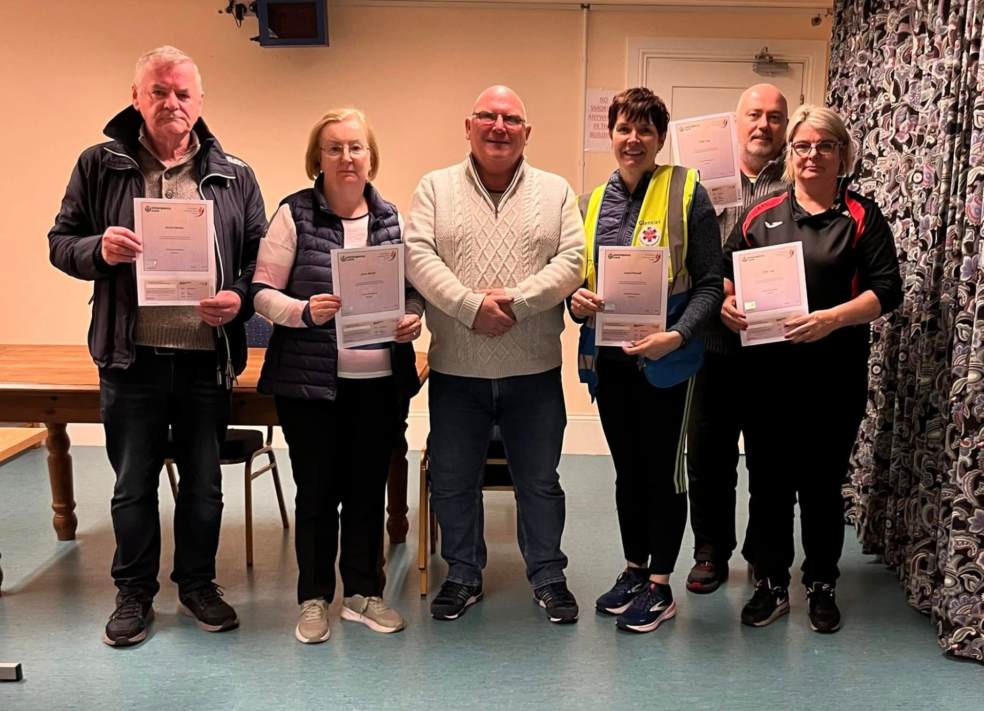 A group of community members holding course certificates after a training session